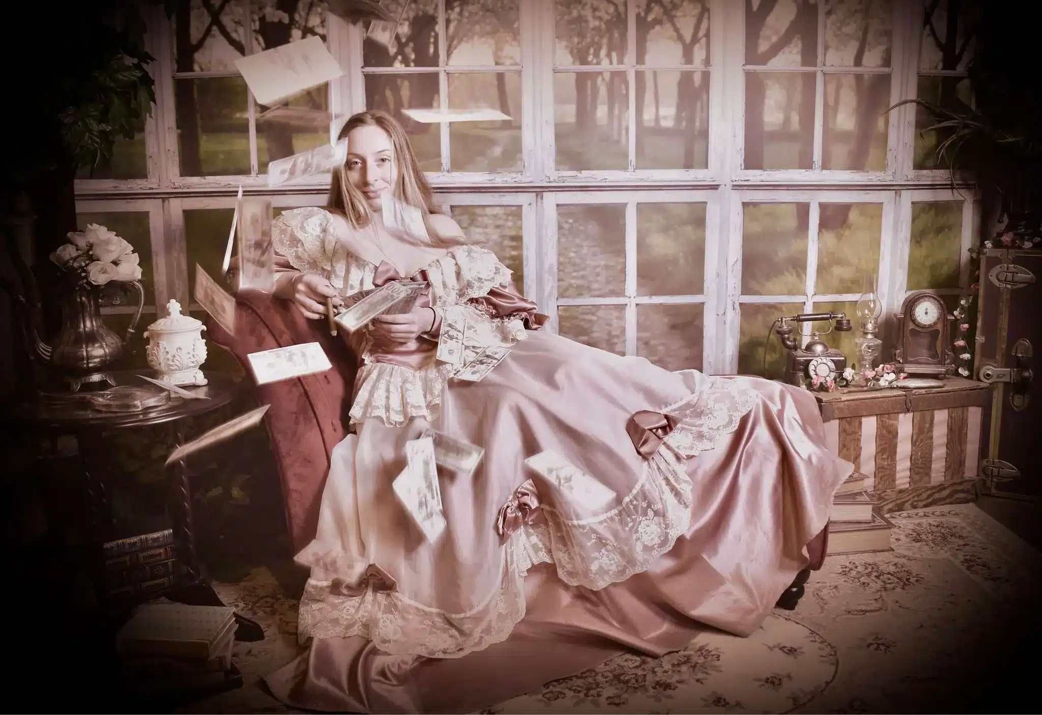 A woman in a vintage pink dress lounges on a sofa by large windows, holding a book as papers fly around her. The scene is decorated with flowers, an old telephone, and antique objects, giving a nostalgic, whimsical feel.